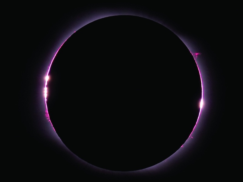 Der dunkle Mond ist von einem violetten Korona-Ring umgeben, an manchen Stellen leuchtet die Sonne über den Rand.