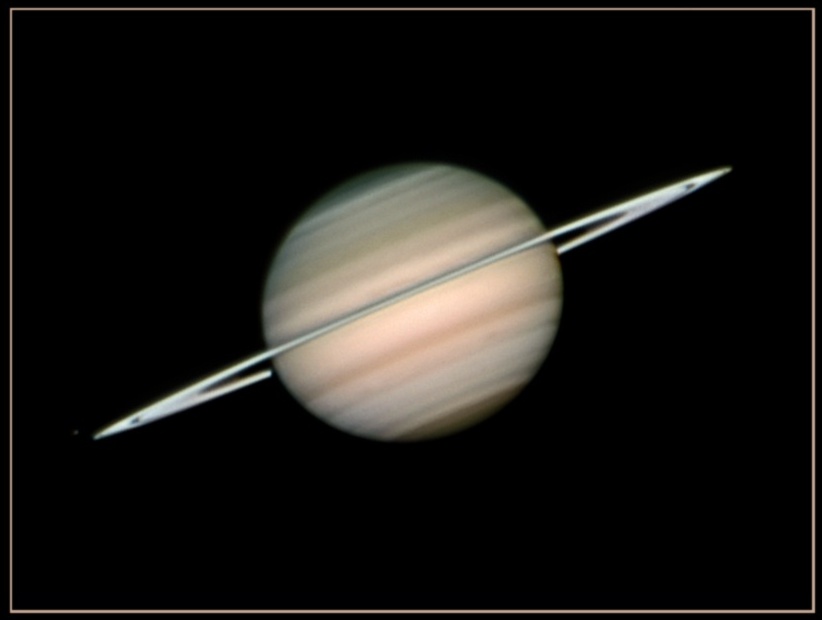 Der Planet Saturn ist von der Seite zu sehen, er liegt leicht diagonal im Bild, die Ringe sind fast von der Kante zu sehen.