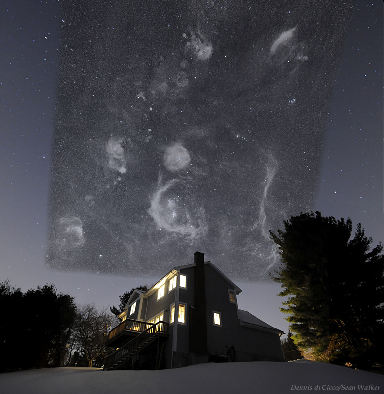 Über einem Haus mit erleuchteten Fenstern und Bäumen ist ein dunkelgrauer Himmel, auf dem ein Bild mit zahlreichen Nebeln montiert ist.