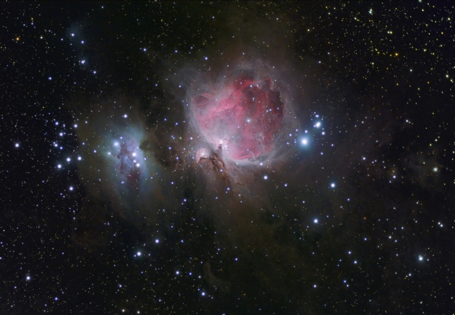 Mitten im Bild leuchtet der Orionnebel, einer der berühmtesten Nebel am Himmel, umgeben von einigen blau leuchtenden Sternen.