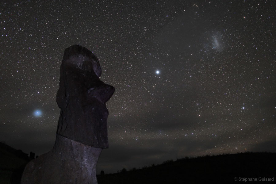 Über Moai auf Rapa Nui (Osterinsel) leuchtet ein sternklarer Himmel mit den Magellanschen Wolken und Canopus.