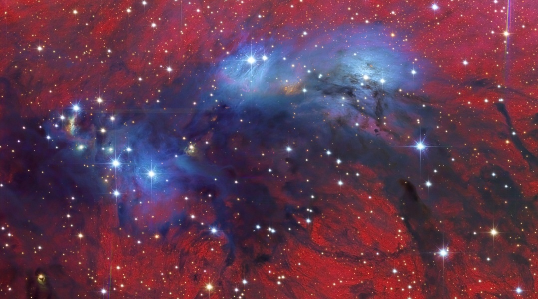 In der Mitte eines leuchtendroten Nebelfeldes mit Sternen befindet sich ein blauer Nebel.