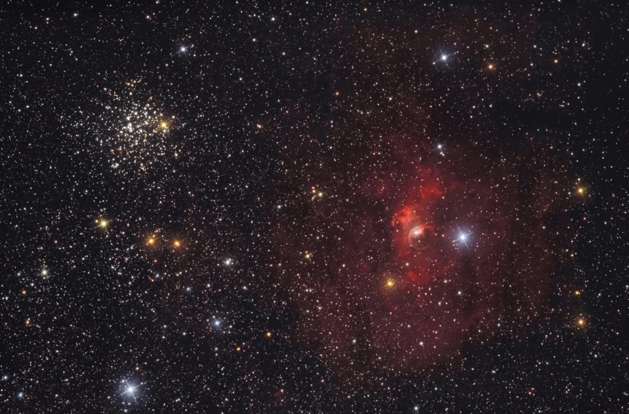 Links im Bild ist ein gesprenkelter, kompakter Sternhaufen, rechts ein Nebel, der Hintergrund ist voller kleiner Sterne mit einigen größeren Gestirnen dazwischen.