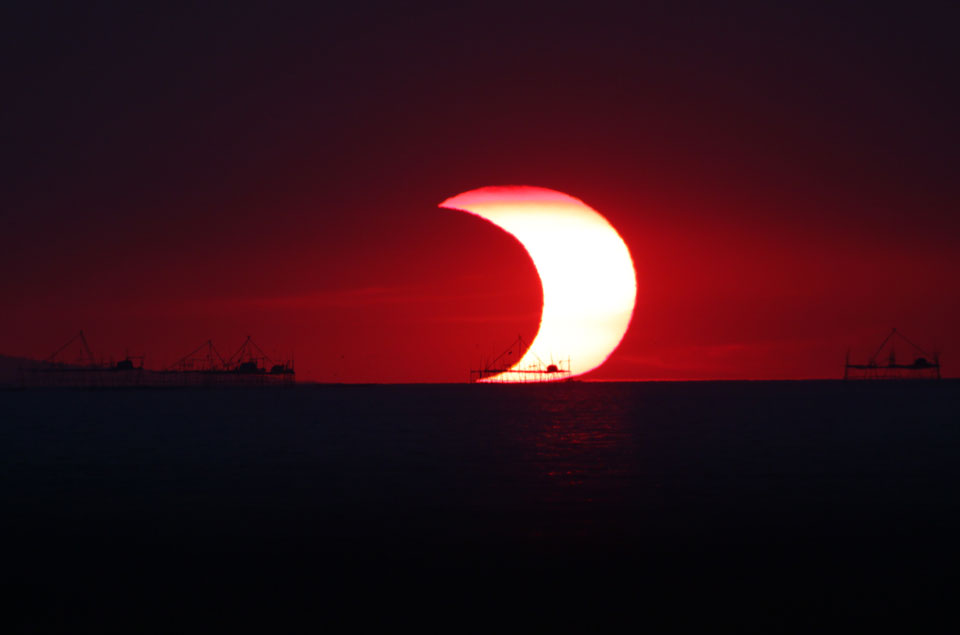 Siehe Beschreibung. Sonnenfinsternis über der Bucht von Manila auf den Philippinen. Ein Klick auf das Bild lädt die höchstaufgelöste verfügbare Version.
