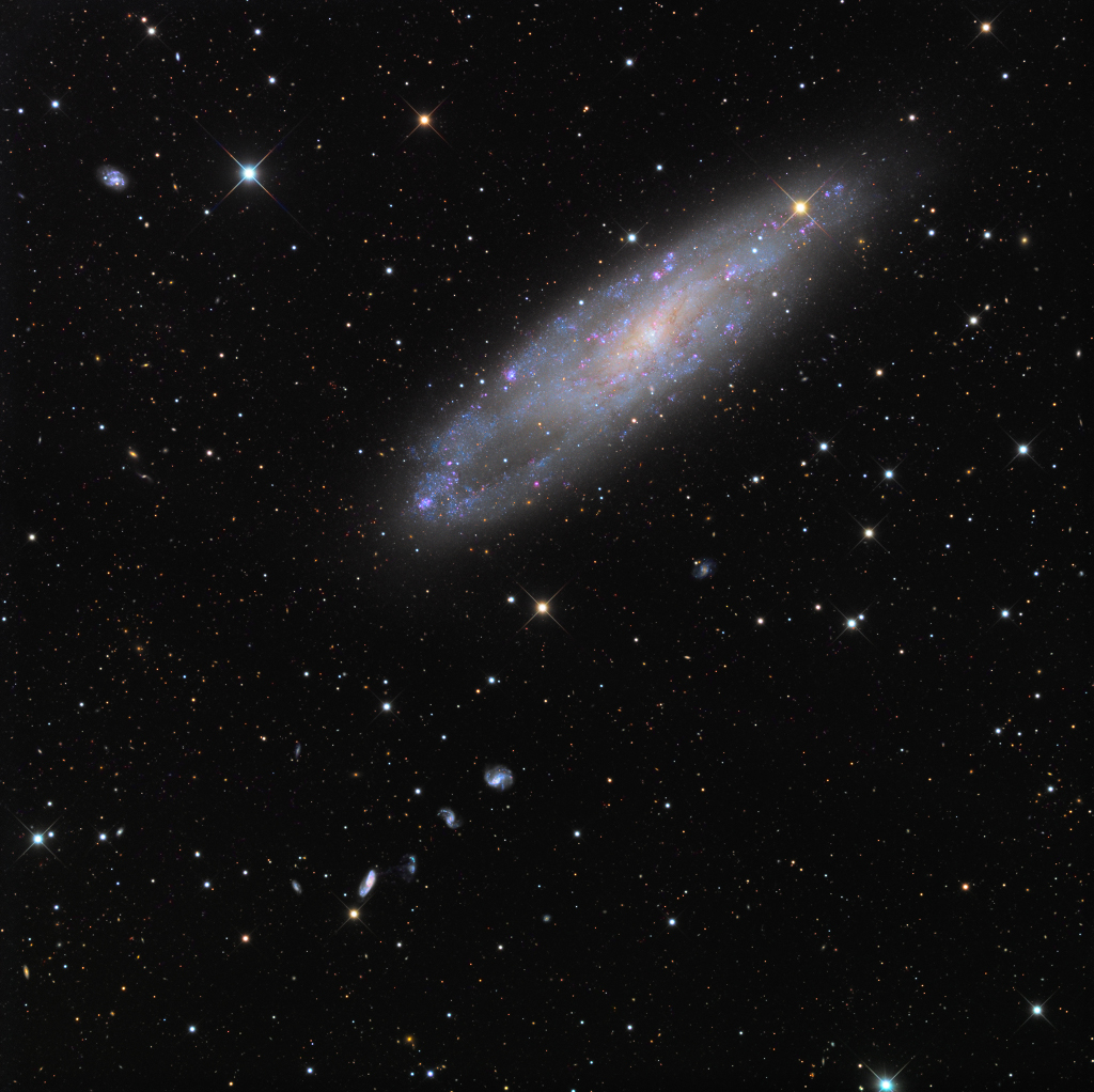 Siehe Beschreibung. Die von der Kante sichtbare Nadelöhrgalaxie, im Hintergrund die Burbridge-Kette; Ein Klick auf das Bild lädt die höchstaufgelöste verfügbare Version.