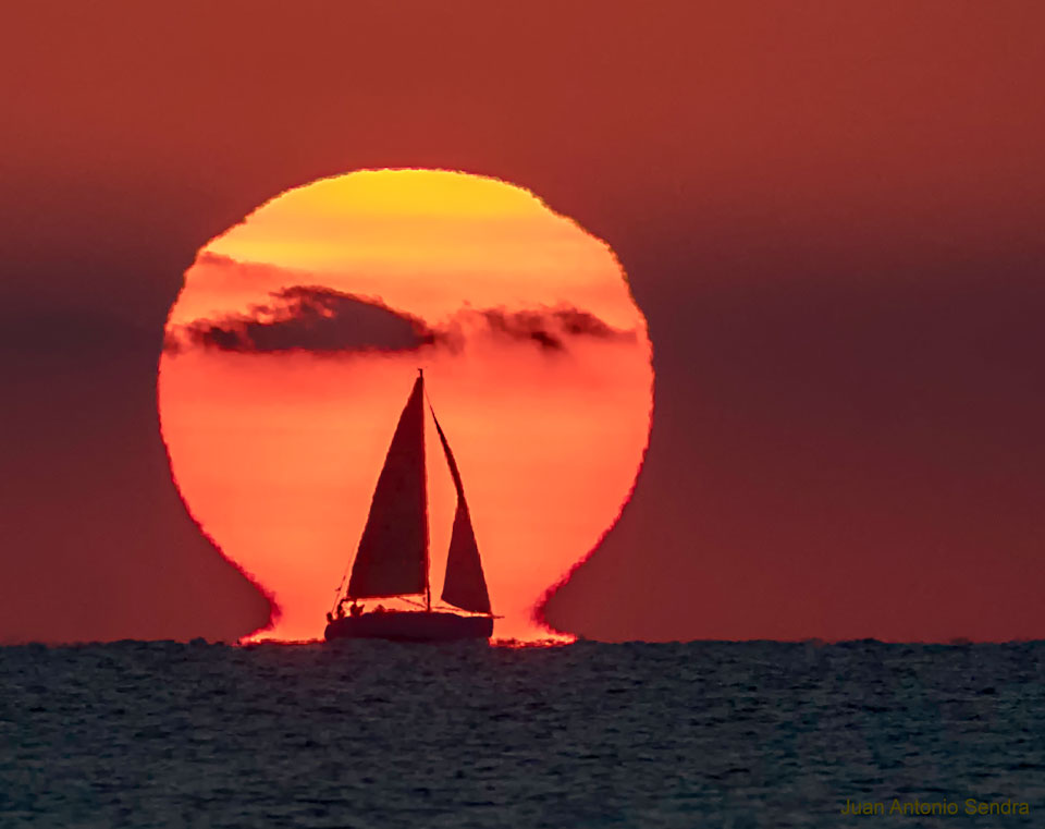 Auf diesem Foto, das über dem Mittelmeer in der Nähe von Valencia in Spanien fotografiert wurde, wieht die Sonne durch eine Luftspiegelung wie der griechische Buchstabe Omega aus.
