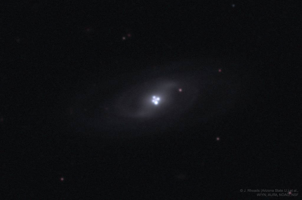 Das Einsteinkreuz im Sternbild Pegasus. Eine kleine schwache Galaxie mit vier hellen Punkten in der Mitte.