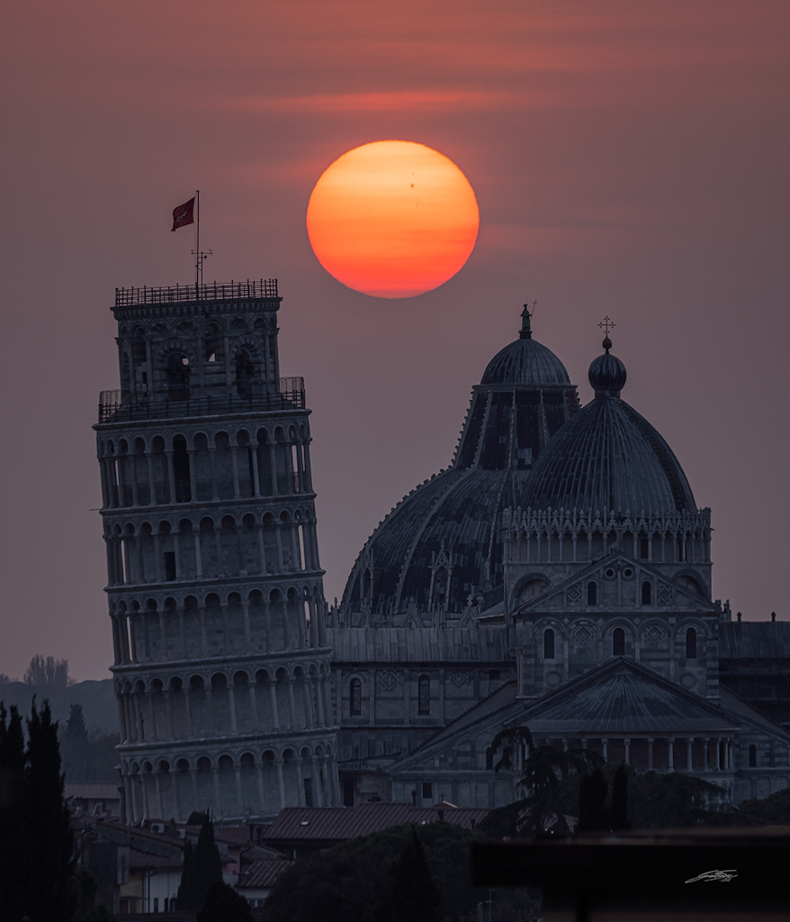 Sonnenuntergang mit Sonnenflecken hinter dem Schiefen Turm von Pisa.