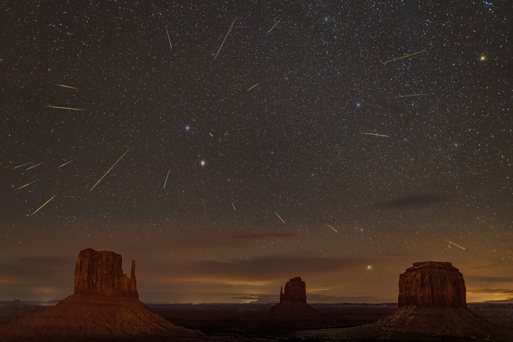 Das Bild zeigt Geminiden-Meteore über dem Monument Valley mit den Mittens und der Merrick Butte.