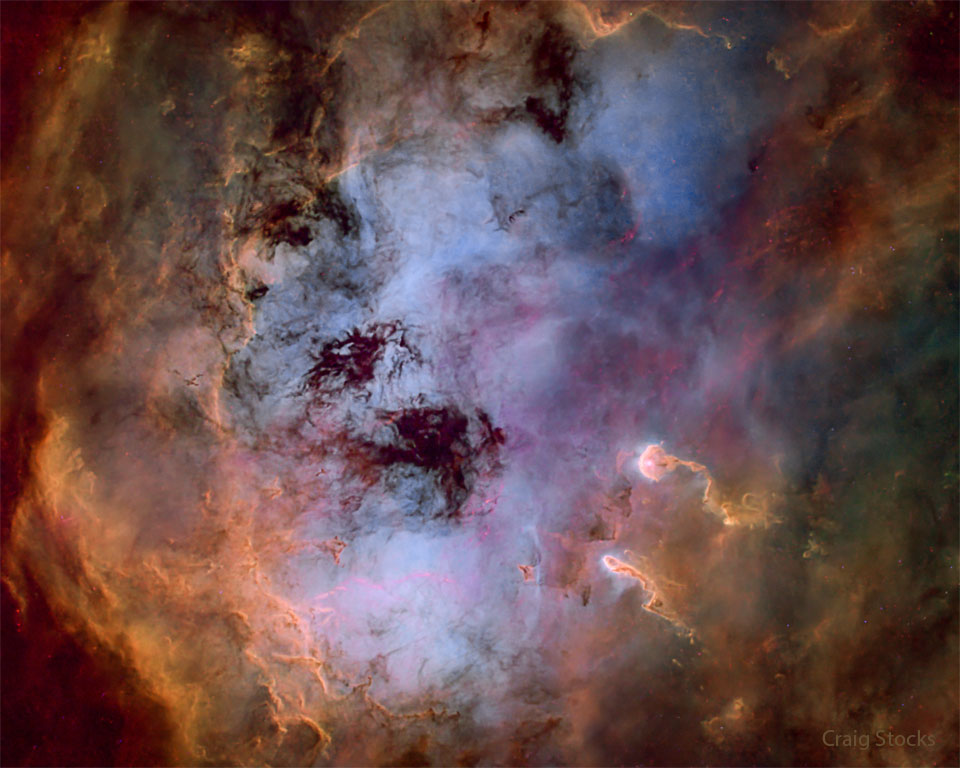 Das Bild zeigt eine leuchtende Sternbildungsregion reich an leuchtendem Gas und dunklem Staub. Zwei staubige Säulen auf der rechts ähneln Kaulquappen.