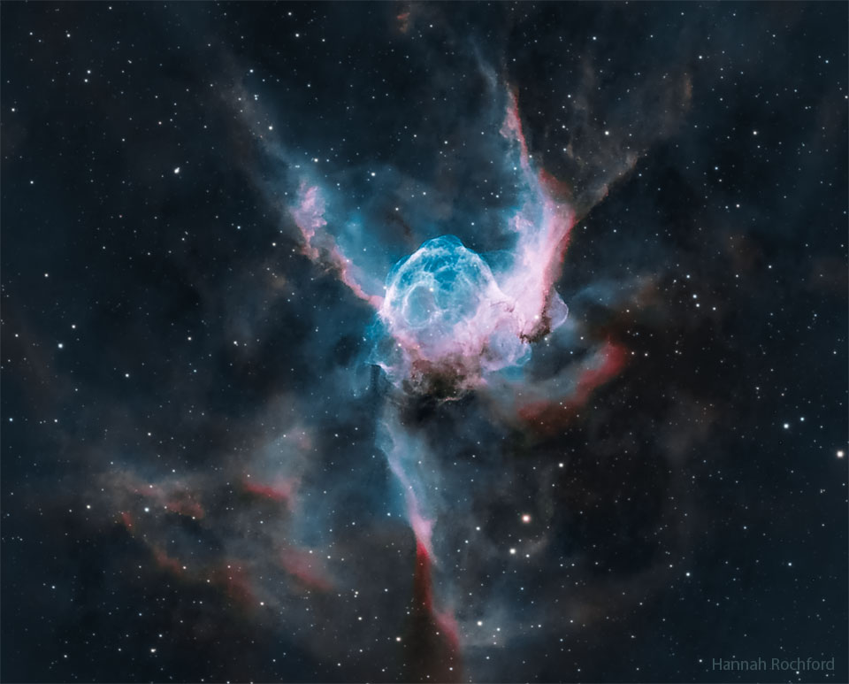 Das Bild zeigt eine helmförmige blaue Blase mit rosaroten Rändern, die von einem Wolf-Rayet-Stern aufgebläht wird. Die Blase sieht aus wie ein Helm mit Flügeln.