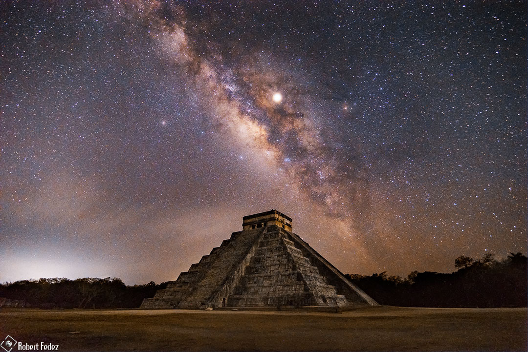 Eine gewaltige Maya-Pyramide steht unter einem Sternenhimmel mit der Milchstraße und den Planeten Saturn und Jupiter.