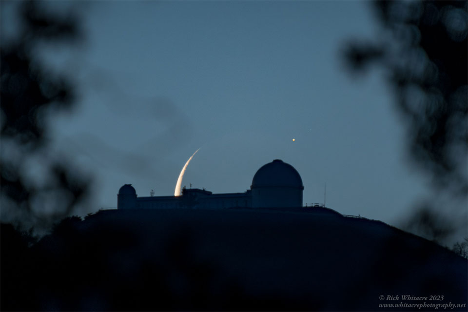 Hinter der Silhouette eines Observatoriums ragt die Spitze der Mondsichel hervor, über einer Kuppel leuchtet Jupiter.