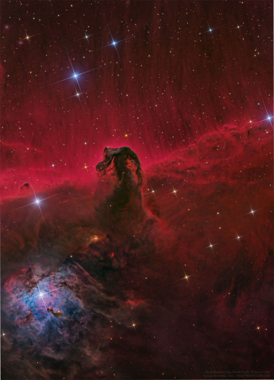 In der Bildmitte befindet sich eine dunkle Wolke, die an ein Seepferdchen erinnert, dahinter leuchtet eine rote Nebelwand, die nach oben hin in Fasern ausläuft. Übers Bild sind Sterne mit Zacken verteilt.