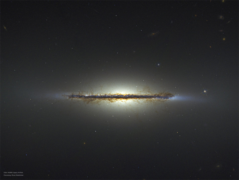 Die Galaxie in der Bildmitte hat eine helle Wölbung und ist exakt von der Kante sichtbar. Quer durch die Wölbung verläuft ein markenterr Staubwulst.