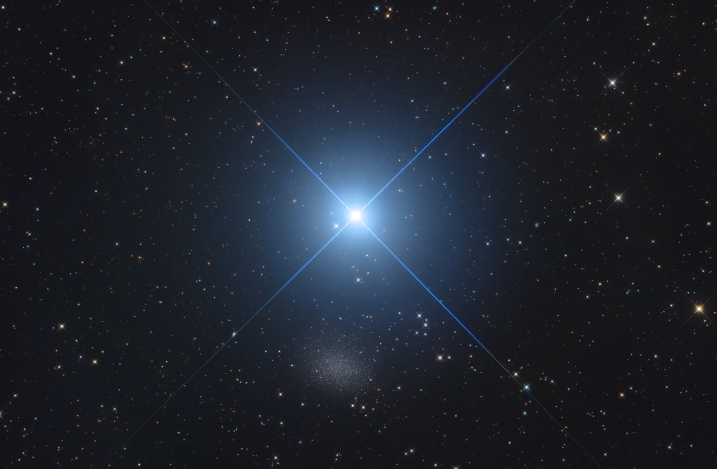 Mitten im Bild leuchtet ein blauer Stern mit markanten Zacken, darunter ist ein blasser, verschwommener gesprenkelter Fleck.