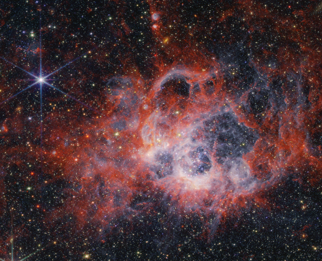 Ein roter Nebel bildet eine netzartige Höhlung, die innen hell beleuchtet ist. Außen sind zahllose Sterne verteilt.