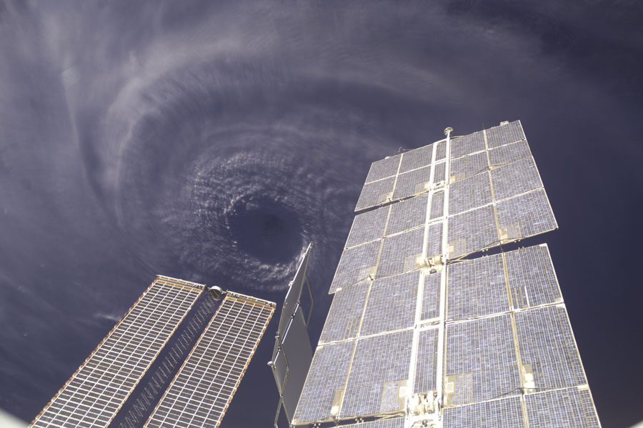Hinter den Solarpaneelen der Internationalen Raumstation wirbelt der Sturm Ivan um sein gewaltiges Auge.