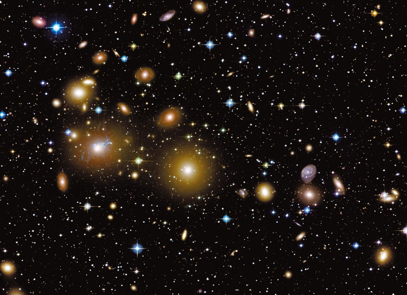 Im Bild ist eine dichte Ansammlung von Galaxien abgebildet, die gelblich leuchten und diffus wirken.