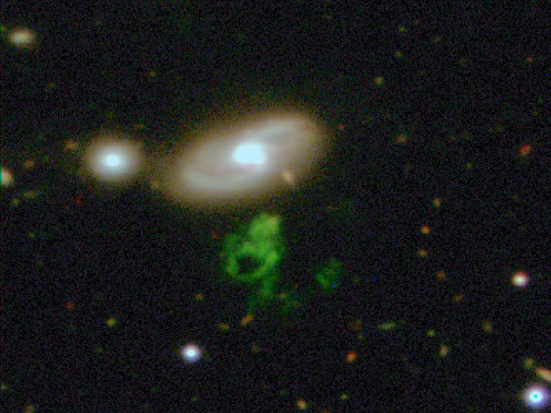Das Bild zeigt zwei verschwommene elliptische Flecken mit hellem Kern, in der Mitte leuchtet unter dem größeren Fleck ein grünes Gebilde, das an keine bekannte Struktur erinnert.