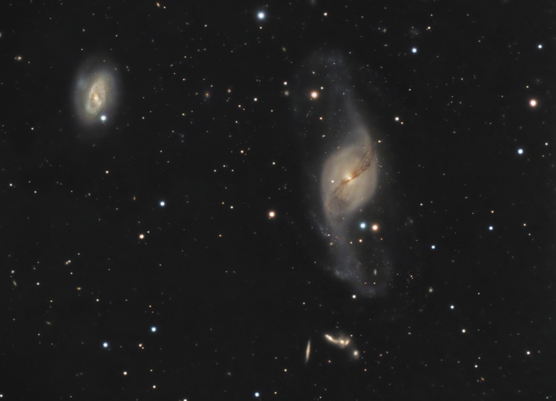 Im Bild sind zwei Galaxien zu sehen, links oben eine kleinere, rundliche und rechts neben der Mitte eine größere mit nach oben und unten herausgezogenen Spiralarmen.