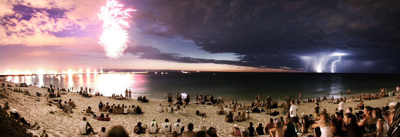 An einem Strand sitzen Menschen und beobachten ein Feuerwerk (links), rechts am Horizont blitzt ein Gewitter, und in der Mitte ist zwischen Wolken Komet McNaught sichtbar.