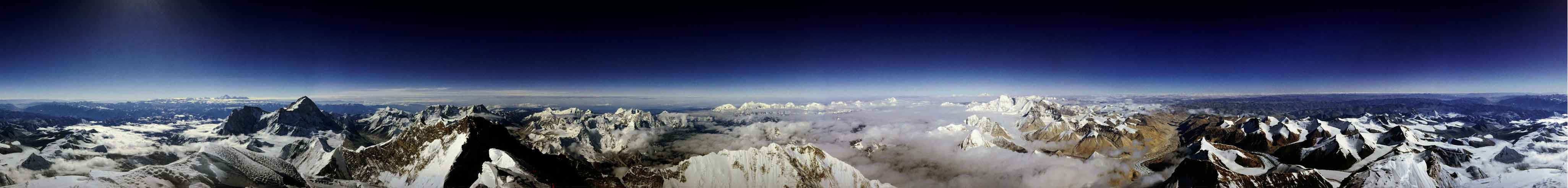 Das sehr breite Panorama zeigt eine Berglandaschaft, über der sich ein sehr dunkler blauer Himmel wölbt.