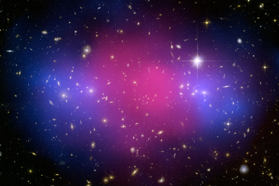 Im Bild sind Galaxien verstreut, in der Mitte leuchtet ein magentafarbener Nebel, links und rechts davon leuchten kleinere blaue Nebel.