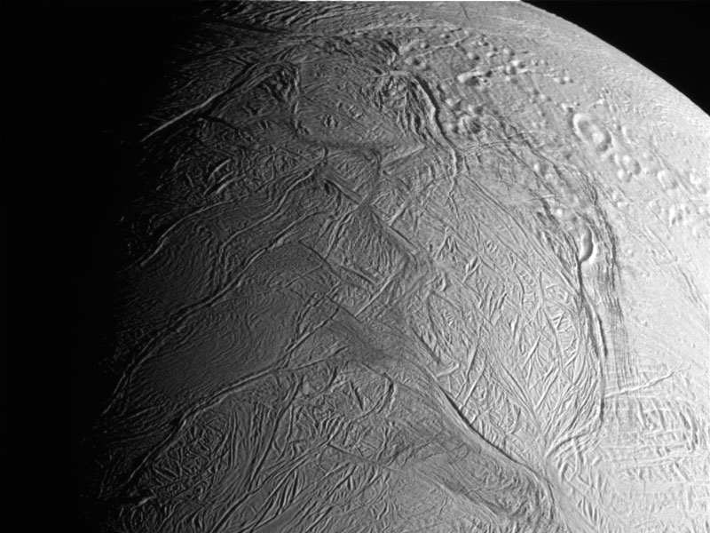 Die faltige Oberfläche von Enceladus ist oben von Kratern akzentuiert.
