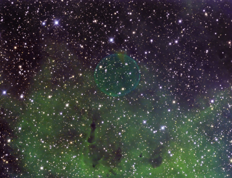 Das Bild zeigt viele Sterne, im unteren Teil leuchtet ein grüner Nebel und in der Mitte ist eine grünliche, sehr gleichmäßige Blase.