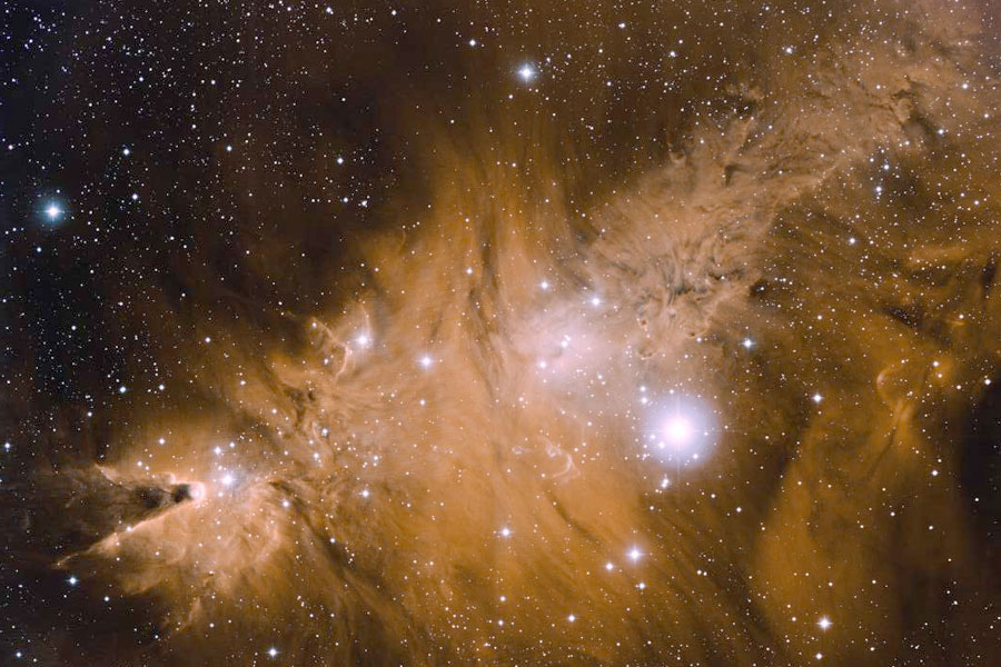 Links ragt eine kegelförmige dunkle Säule mit dunkler Spitze in einen orangefarbenen Nebel hinein, im ganzen Bild sind Sterne verstreut.