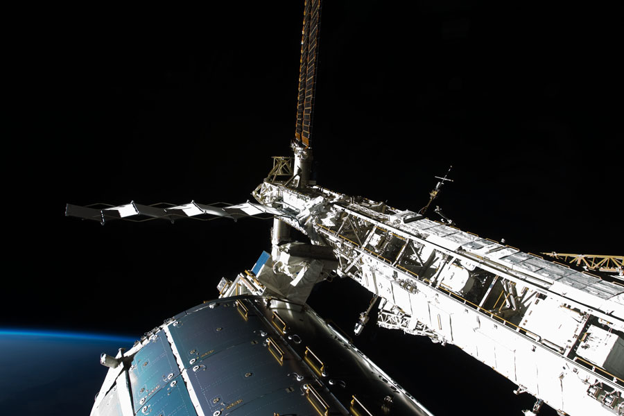 An der Struktur der ISS befindet sich ein Astronaut, der Reparaturarbeiten durchführt.