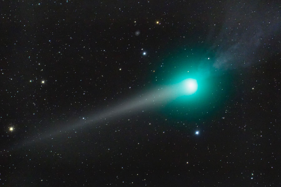 Im Bild ist ein Komet mit türkiser Koma abgebildet, einer seiner Schweife reicht nach links, ein kürzerer nach rechts.