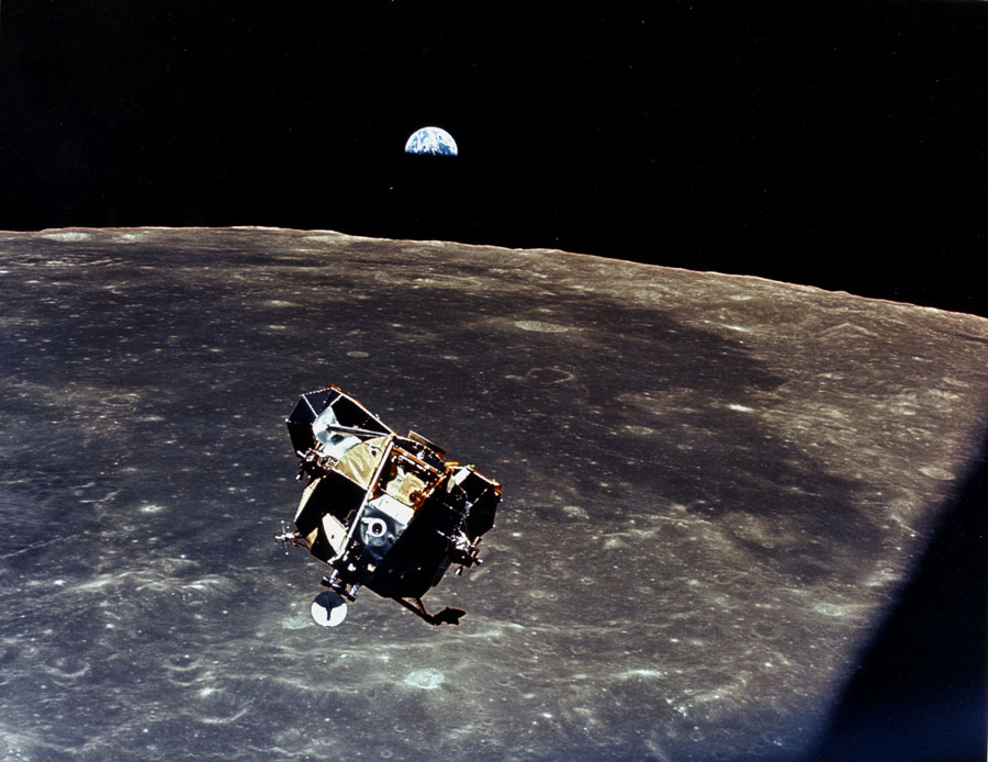 Im Hintergrund geht die Erde über dem Mond auf, davor schwebt die Mondlandefähre.