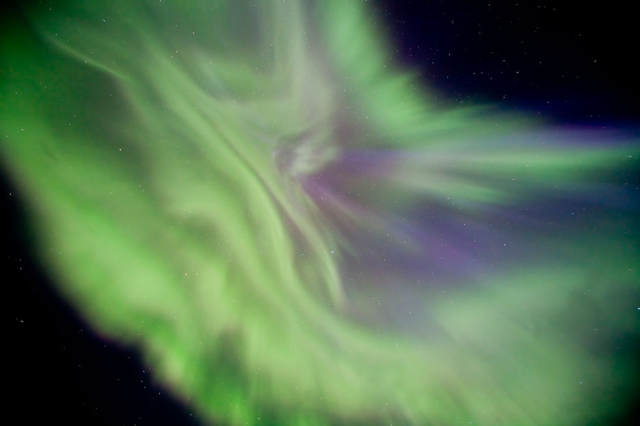 Am dunklen Himmel ist ein bildfüllendes grünes Polarlicht zu sehen.