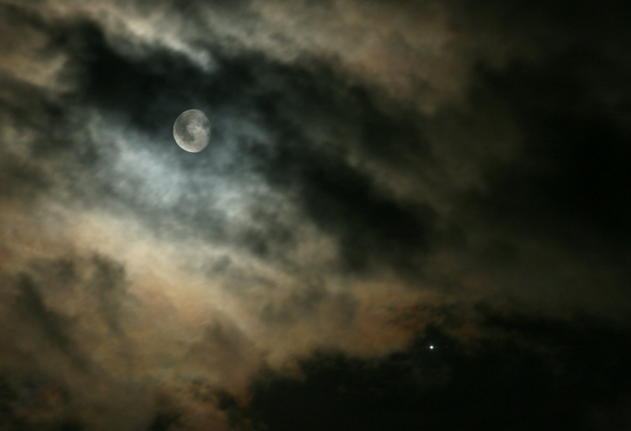 Hinter Wolken leuchtet der Mond, rechts unten Jupiter mit den galileischen Monden.