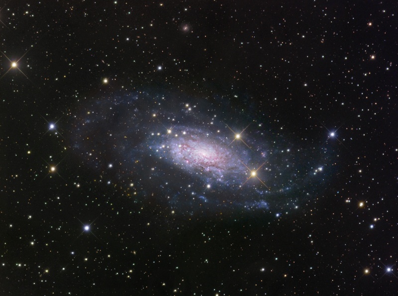 Das Bild zeigt eine von Sternen umgebene Galaxie, die wir schräg von oben sehen.