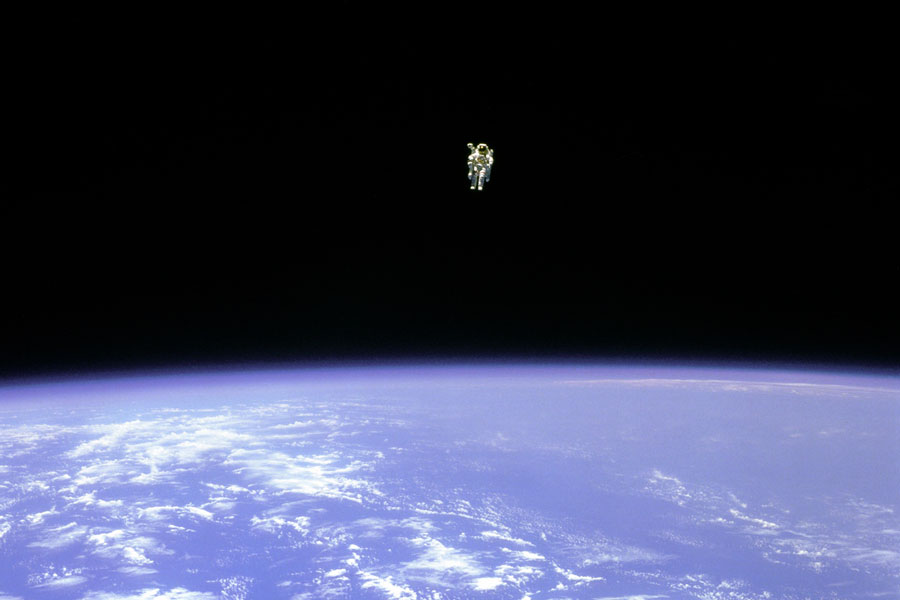 Über dem Rand der Erde schwebt ein weit entfernter Astronaut ohne Leine.