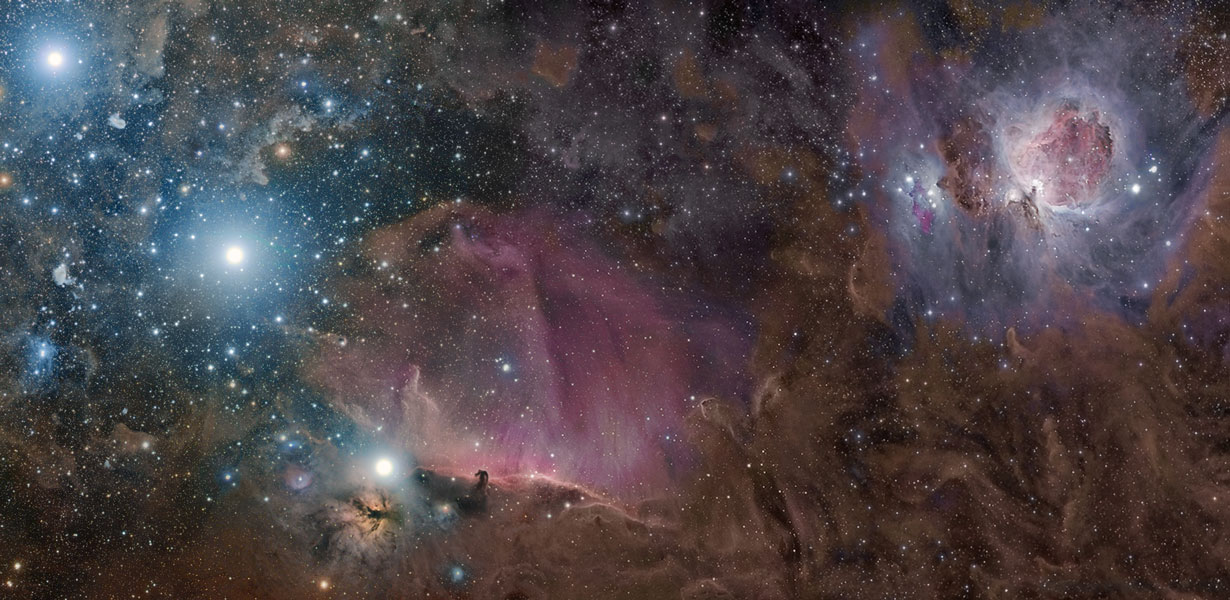 Das staubbedeckte Bildfeld zeigt rechts oben den Orionnebel, unten sind der Pferdekopfnebel und der Flammennebel, links oben leuchten zwei Sterne im Gürtel des Orion.