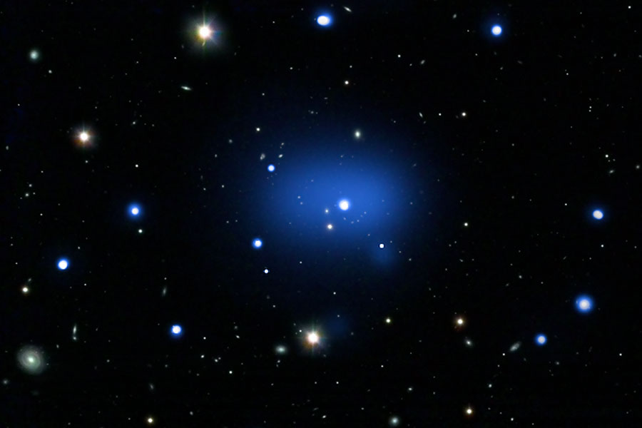 Im Bild sind wenige markante Sterne verteilt, in der Mitte leuchtet ein blauer Nebel mit einem Stern in der Mitte.