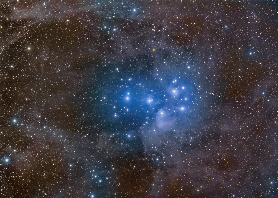 Das Bild ist voller Sterne und molekularem Gas. In der Mitte leuchtet ein Sternhaufen, der von blauen Nebeln umgeben ist.