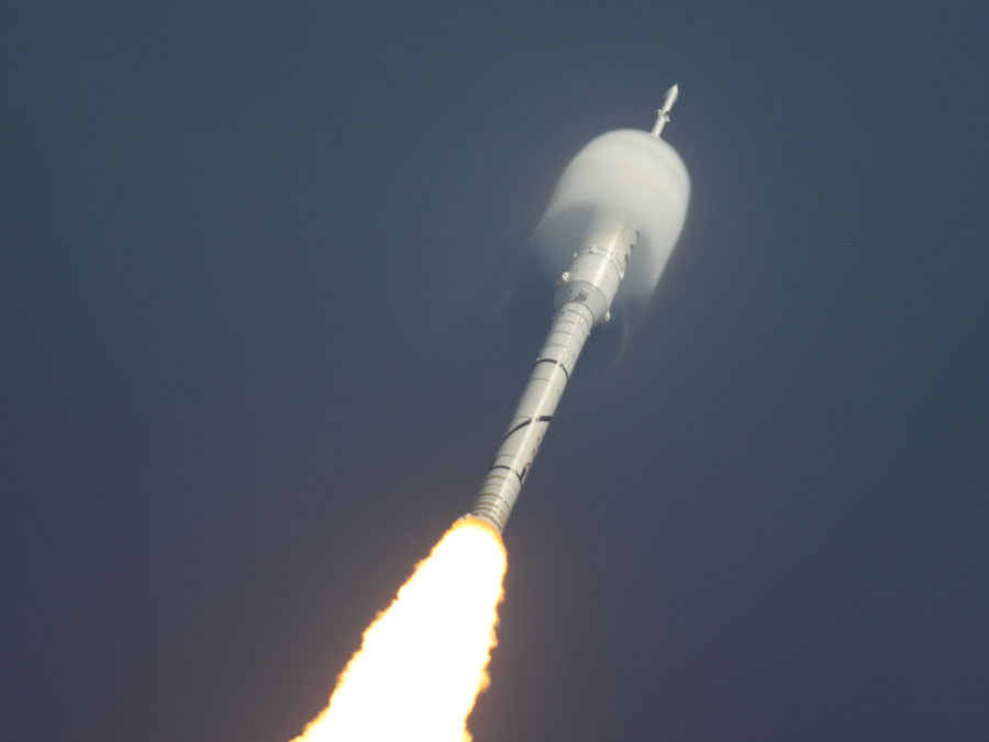 Eine startende Rakete ist oben von kondensiertem Wasserdampf umgeben, der entsteht, wenn ein Flugkörper die Schallmauer durchbricht.