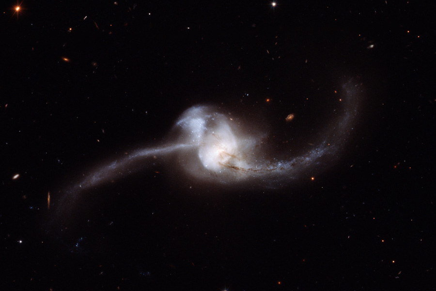 In der Bildmitte sind zwei Galaxien nur als eine erkennbar, so stark sind sie verworren. Nach links und rechts sind lange Schweife aus Sternen und Staub hinausgeschleudert.