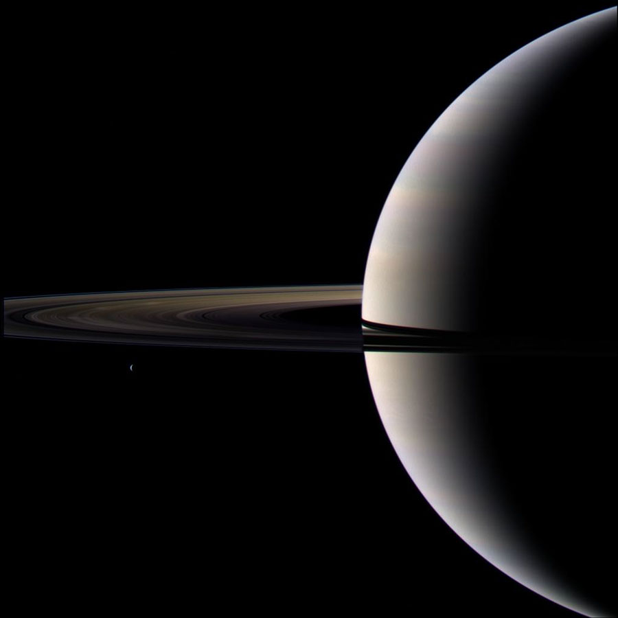 Die Sichel des Riesenplaneten Saturn ragt zur Hälfte von rechts ins Bild, die Ringe reichen bis zum linken Bildrand und sind dort abgeschnitten.