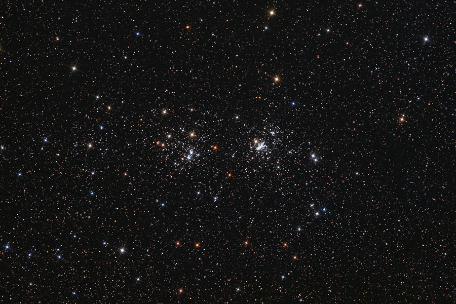 Mitten im Bild sind zwei nah beisammen liegende Sternhaufen, im Hintergrund sind Sterne verteilt.