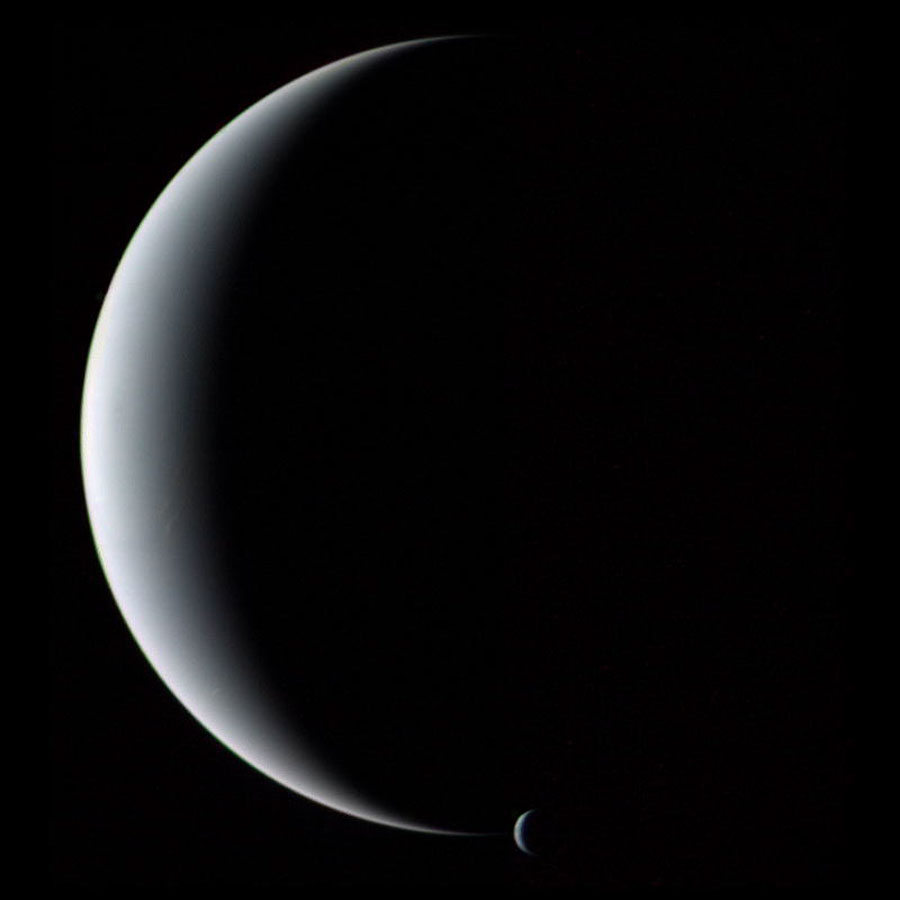 Zwei sehr glatte, matt beleuchtete Kugeln sind als Sicheln zu sehen, 
links der große Neptun und an der unteren Spitze die kleine Sichel des Mondes Triton.