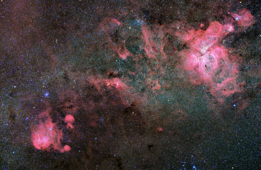Links unten und rechts oben leuchten lebhafte rote Emissionsnebel, vermischt mit dunklen Staubwolken, vor einem Hintergrund aus dicht gedrängten matten Sternen.