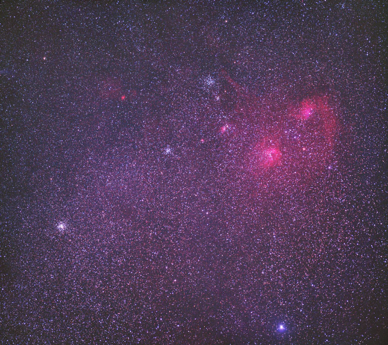 In einem dicht mit Sternen gefüllten Bild leuchten rechts oben zwei magentafarbene Nebel.