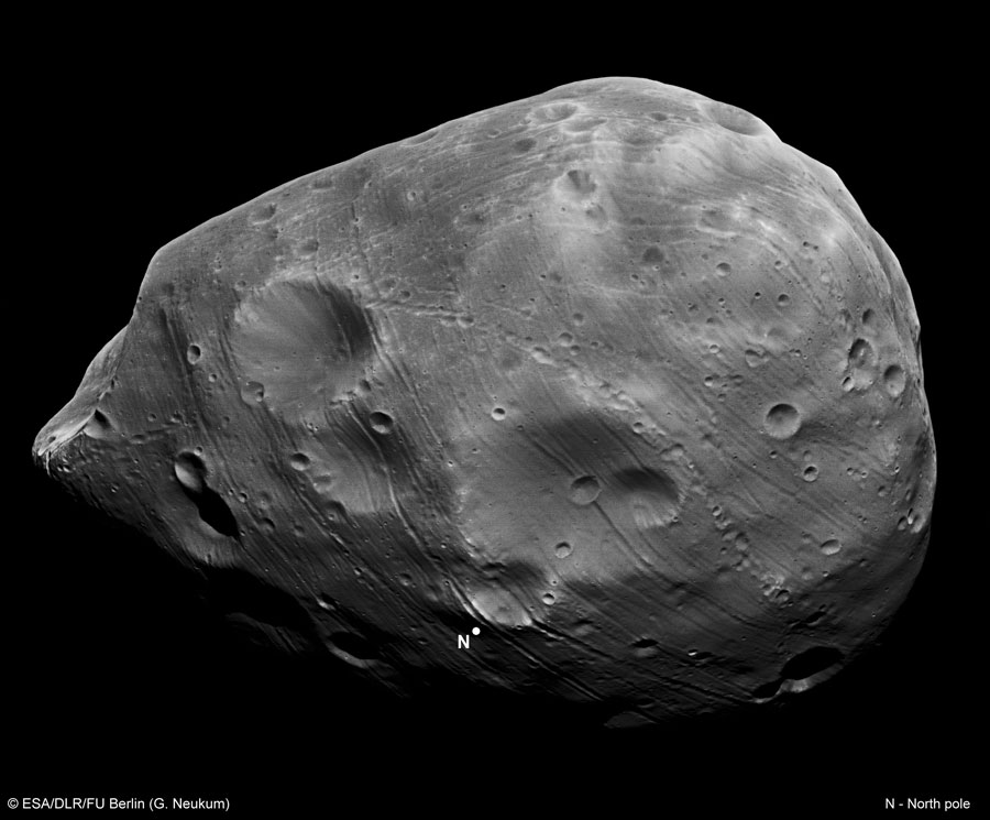 Ein kartoffelförmiger Mond mit Kratern und vielen Streifen ist bildfüllend dargestellt.