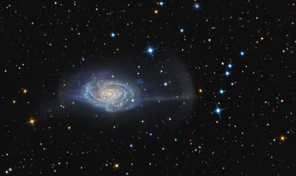 Die überlagerten roten Schalen sind die berechneten Trümmer einer kleinen Begleitgalasie der größeren Galaxie im Bild.